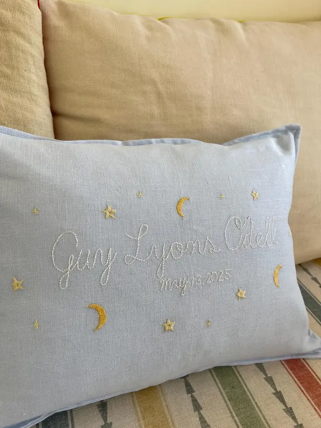 Personalised Handmade Embroidered Linen Cushion, pale blue cushion with name on sofa. 