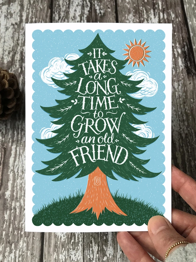 hand holding old friend pine tree card