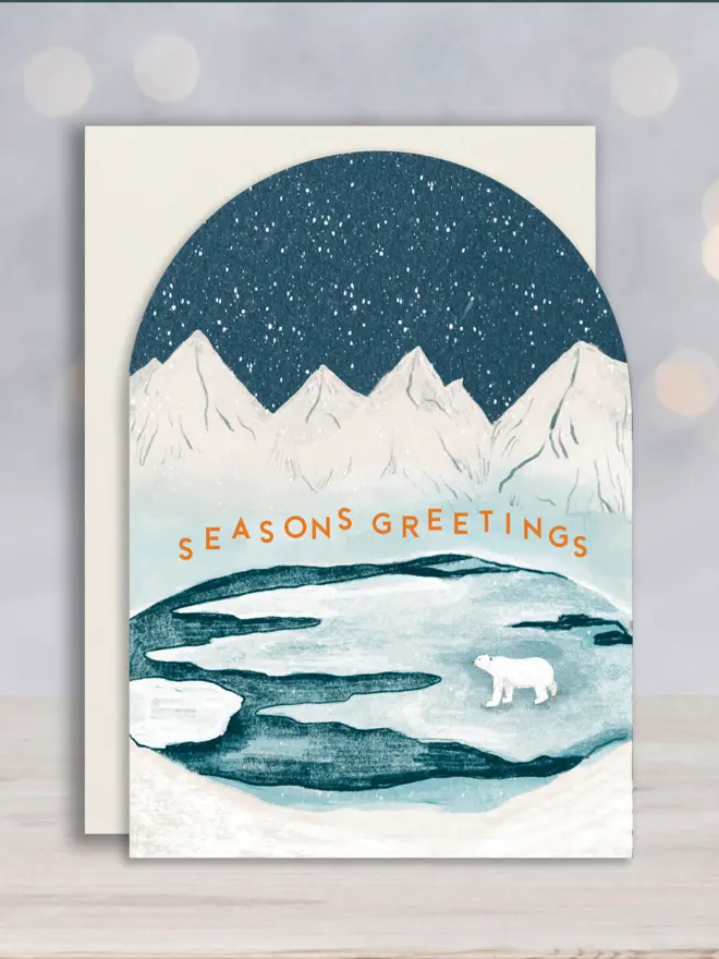 Arched shape Christmas card with white envelope, with an illustrated iceberg scene showing a polar bear under the snowy night sky