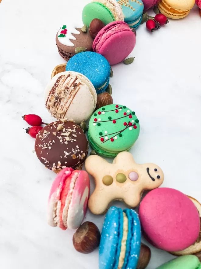 a wreath of colourful macarons with gingerbread men macarons on a marble table