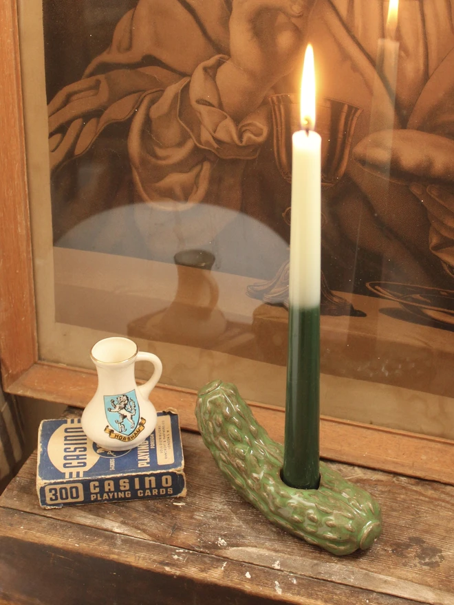 Pickle Candle Holder, a pickle candle holder sitting on a wooden surface with a candle in it. 