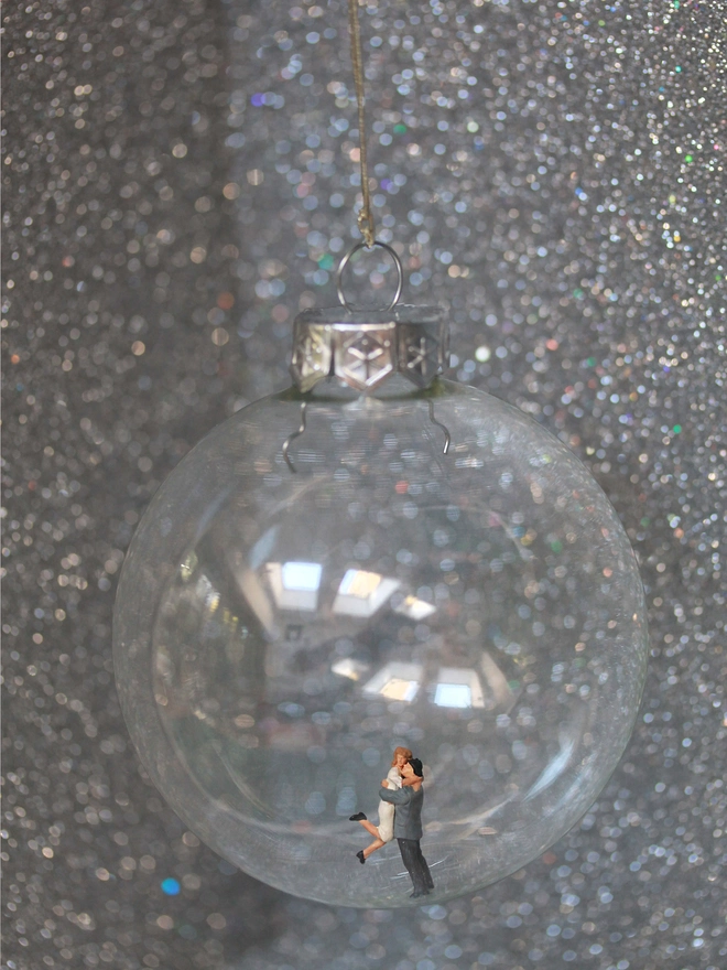 Miniature figure of a hugging couple in a glass Christmas bauble 
