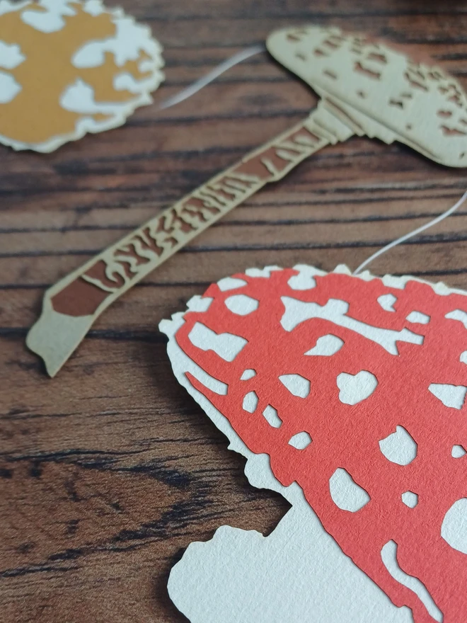 Closeup of Red and White Paper Toadstool Garland Decoration, Beige and Dark Brown Paper Toadstool Decoration, Brown and White Puffball Decoration