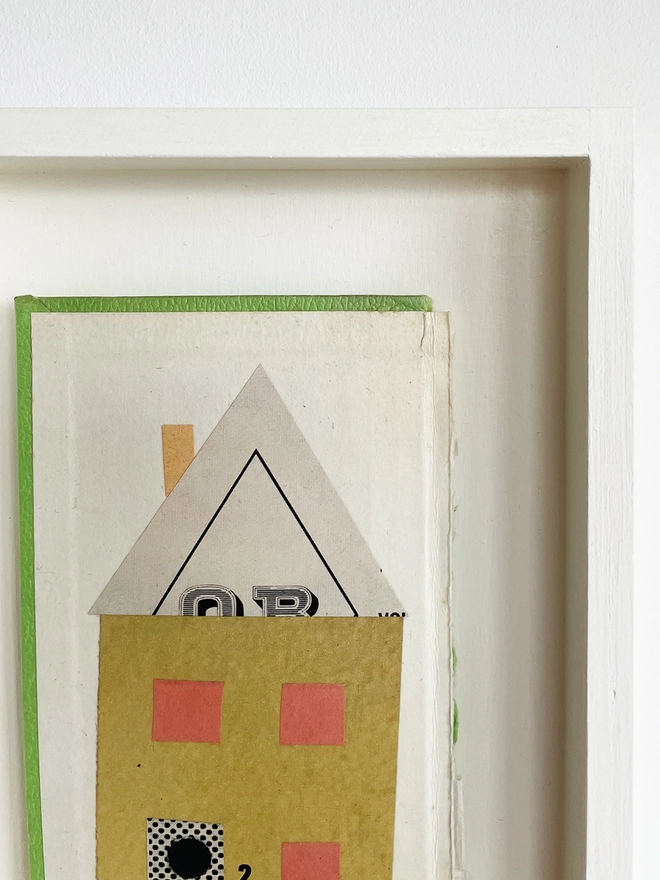 A close up view of a mustard yellow house portrait on a vintage book cover. Float mounted within a hand painted wood box frame.