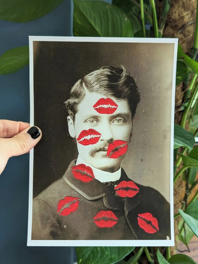 B&W photo print of man covered in embroidered red kisses held against blue background 