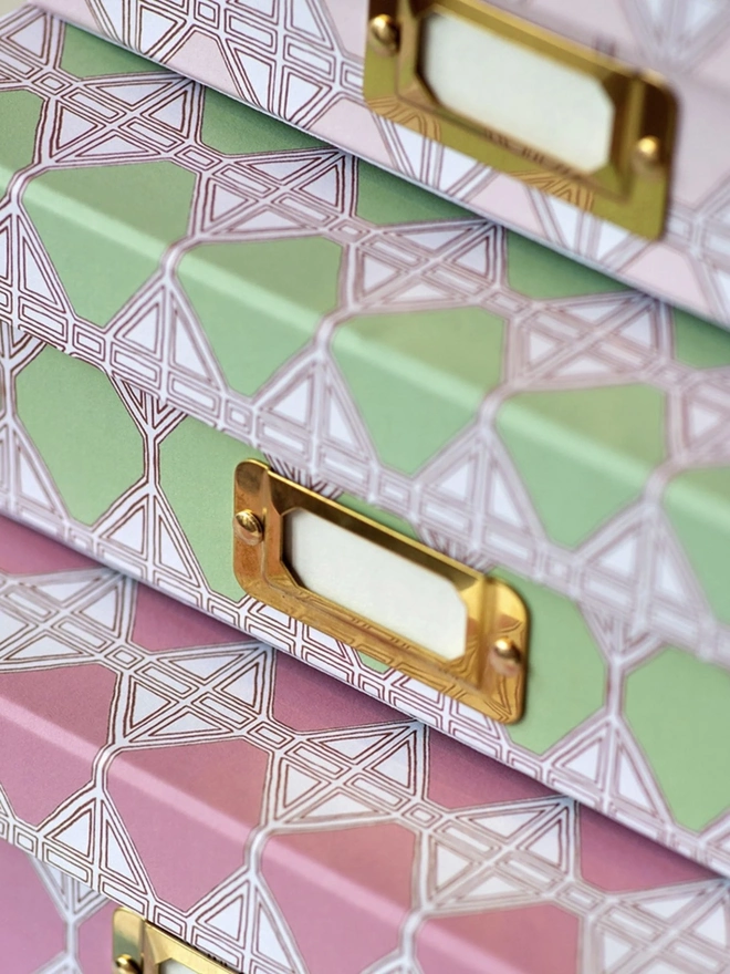 Tijan Lidded Portfolio Box, a collection of colourful portfolio boxes stacked on a plain surface. 