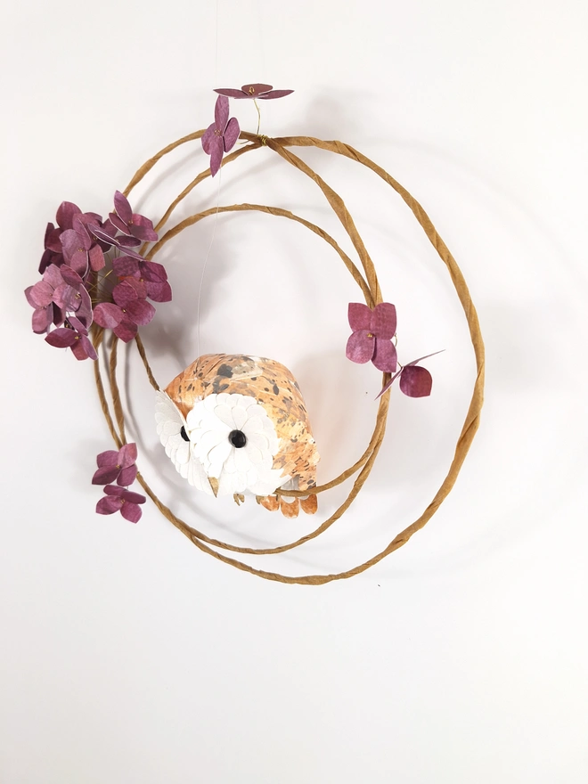 handmade paper sculpture of a baby barn owl, perched on a floral wreath of mulberry hydrangea