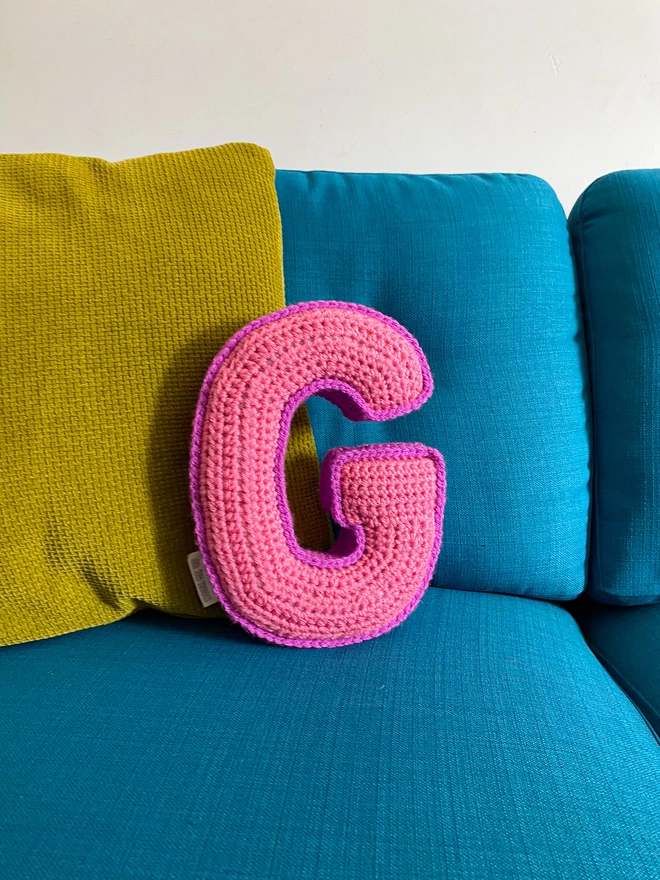 Crochet cushion shaped like the letter G in Pink and Magenta