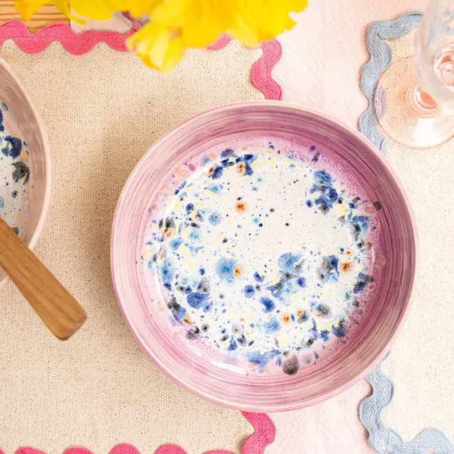 Shoreline Pasta Bowl, a colourful bowl placed on a table setting. It is accompanied by napkins and other items. 
