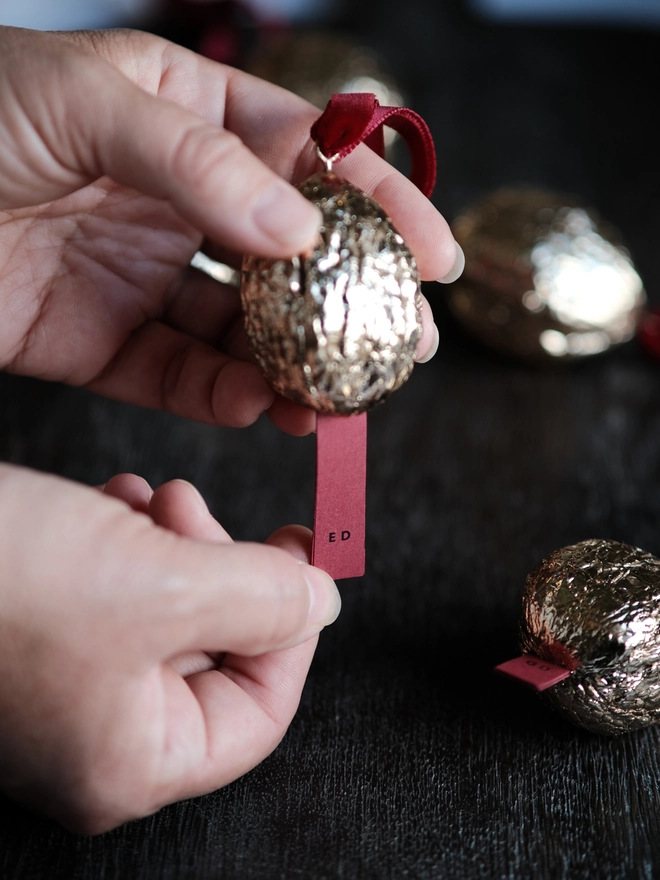 Handmade walnut Christmas ornament with delicate gold gilding, showing the natural shape and grain of the wood. A traditional, nostalgic Christmas tree decoration with timeless old-fashioned charm.