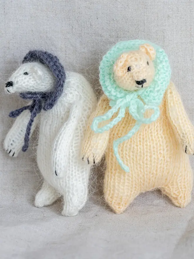 Ottilie The Bear Cashmere Figure, a pair of cashmere bears held by a person against a grey backdrop. 