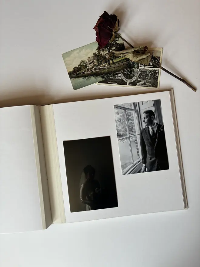 Handmade photograph album displayed open to show bright white page and cloth joint