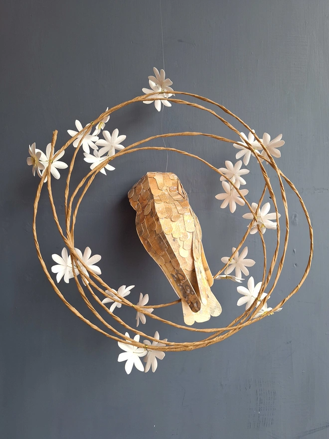 back view of a paper sculpture featuring a barn owl perched on a floral wreath