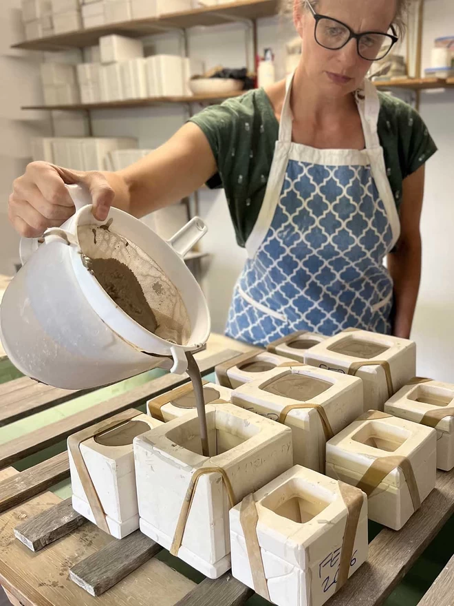  In her studio Katie is filling plaster sugar pot moulds with slip (liquid clay) from a large plastic jug.