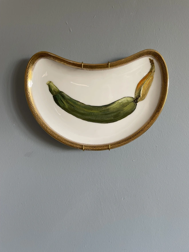 painting of fresh courgette on moon shaped side plate