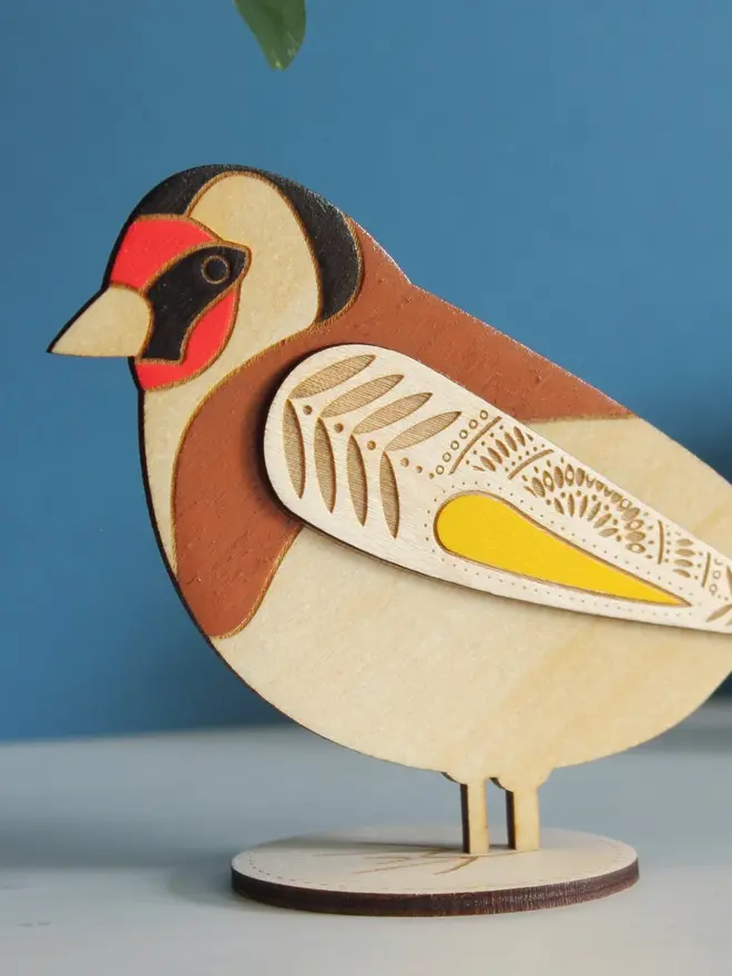 Standing Wooden Goldfinch, wooden bird decoration standing on a platform. 