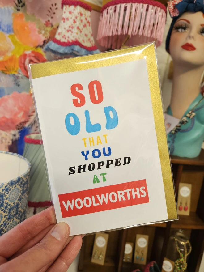 A photograph of the front of a humorous A6 greeting card illustrated using brightly coloured text and the retro shop logo. The text says so old you shopped at Woolworths