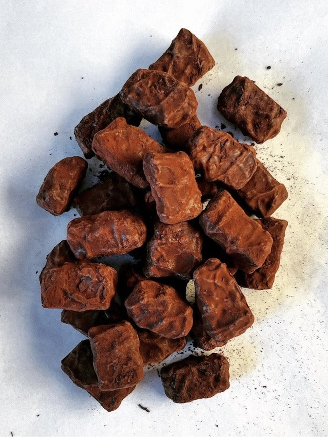 Chocolate Truffles, a pile of chocolate truffles sitting in a pile on a plain white surface. 