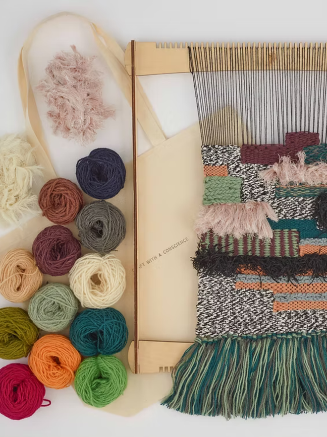 large weaving kit. a large loom on a white surface, with yarn in various colours.