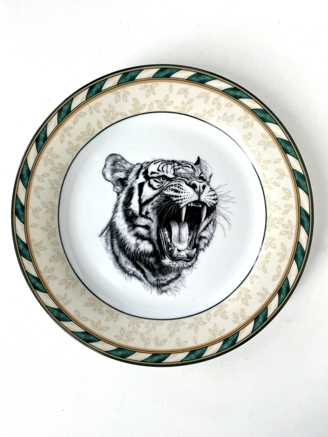 a vintage plate with an ornate border, in the centre of the plate is a vintage style black and white illustration of a tiger roaring