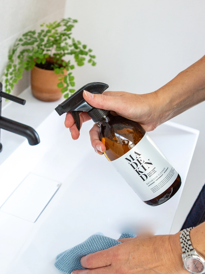 Woman cleaning bathroom with natural cleaning product.