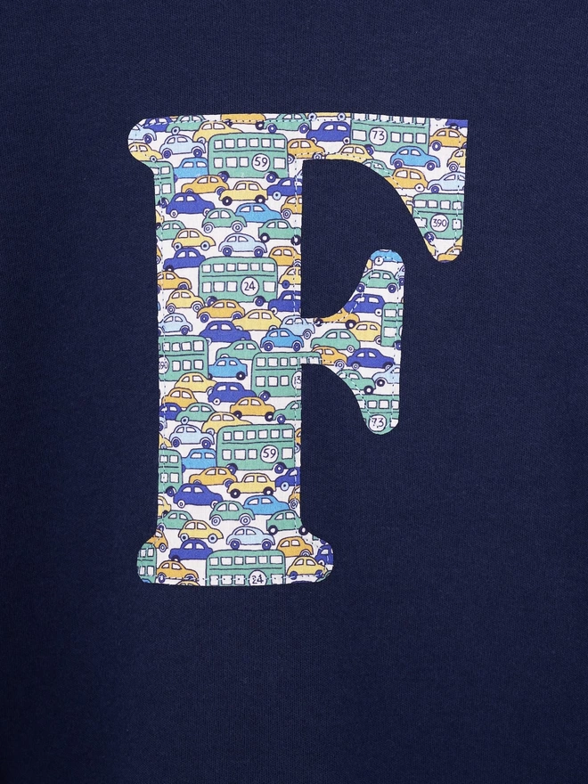 A navy cotton long sleeve t-shirt appliquéd with an initial in a vintage cars and busses Liberty print, a close up of the stitching