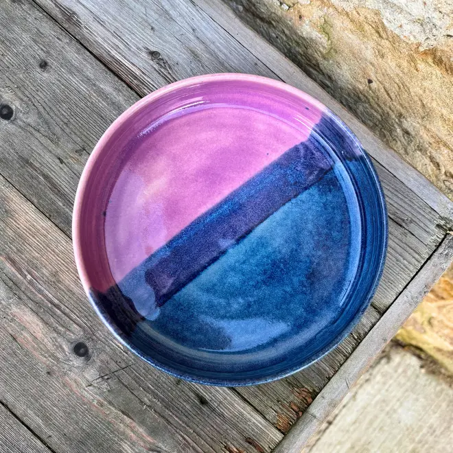 Landscape Pasta Bowl, a colourful pasta bowl on a wooden surface against a brick backdrop. 