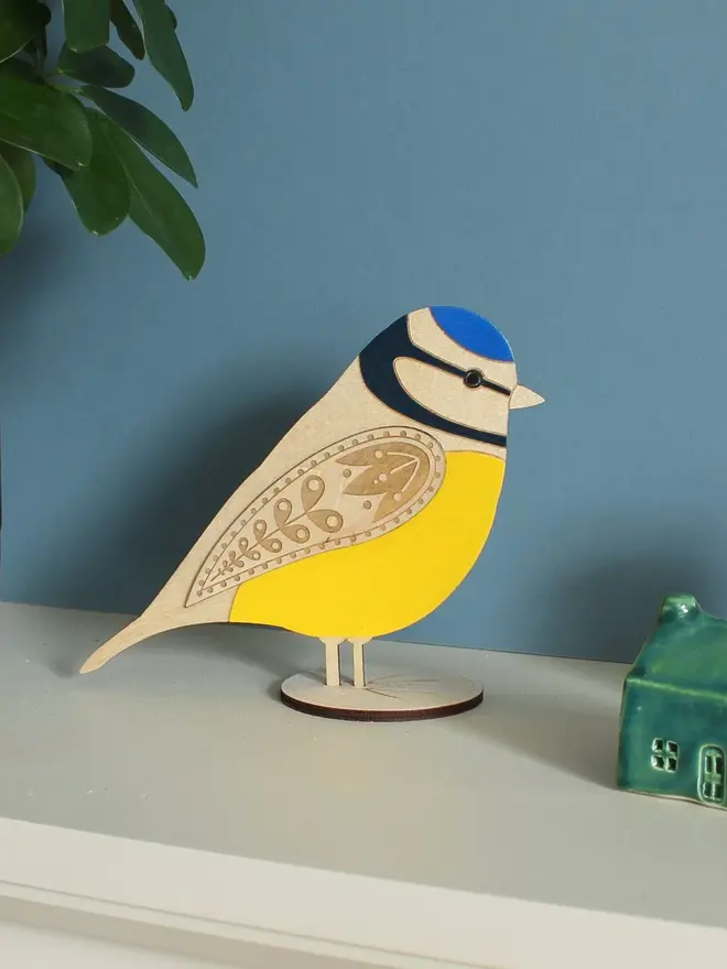 Standing Wooden Blue Tit, yellow wooden bird decoration standing on a platform. 