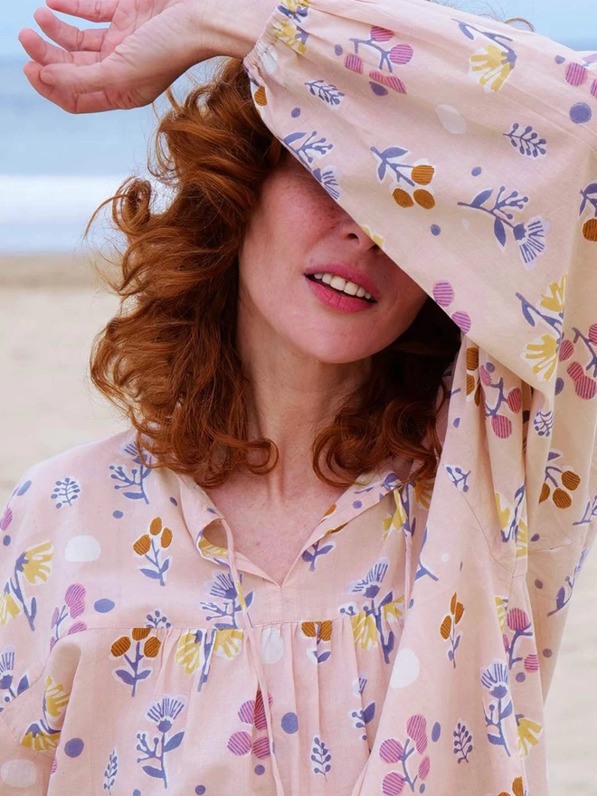 Red hair girl wearing a pale pink pyjama top with a block printed floral design in pastel colours