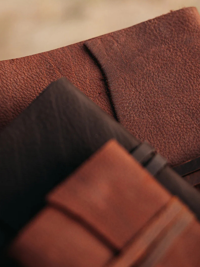 reclaimed saddlery leather journal. a stack of three different sized brown leather  journals.