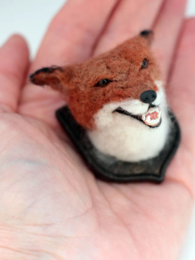 A miniature snarling fox head in the palm of a hand 