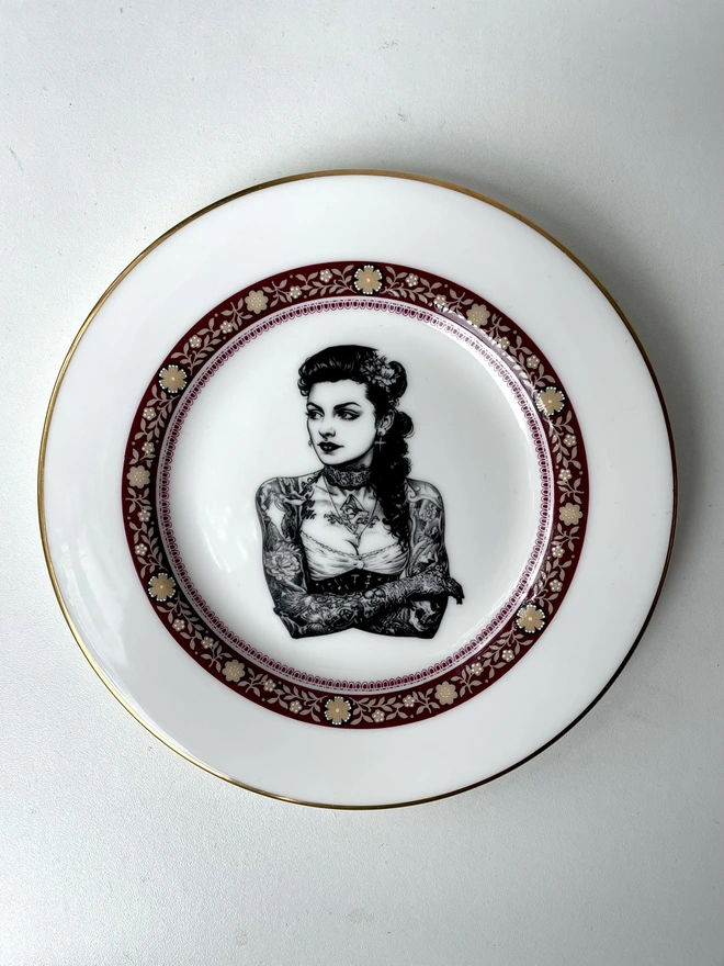 a vintage bone china plate with ornate border has a vintage Tattooed victorian lady in the centre