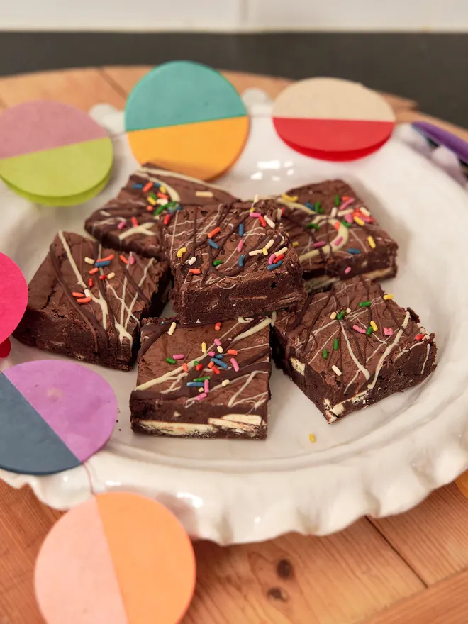 Birthday Brownies - triple chocolate with multicoloured sprinkles on a white plate and colourful bunting