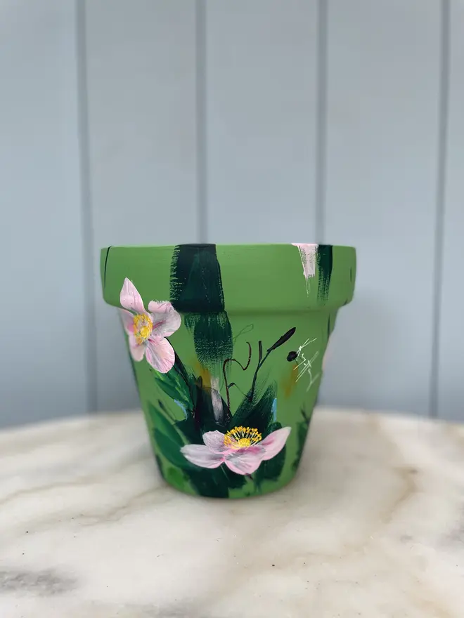 Unique hand-painted terracotta pot featuring pink anemone on a green background