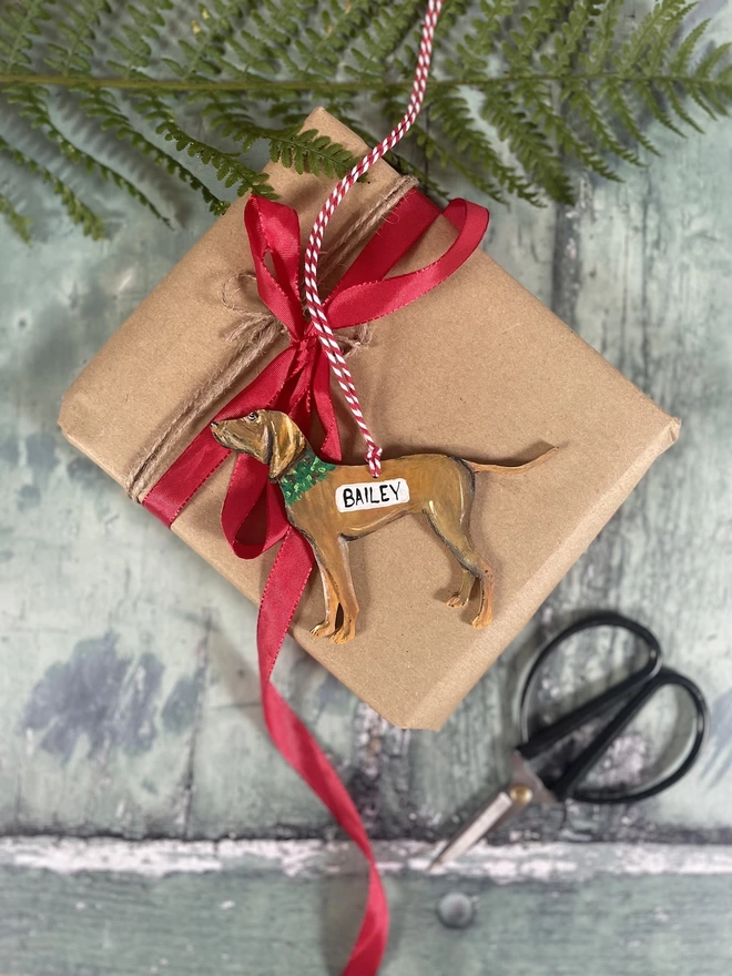 A vizsla dog Christmas decoration placed on a wrapped present