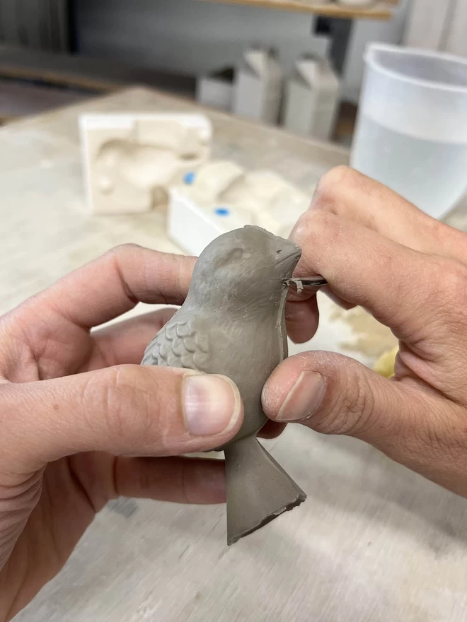 Katie Brinsley is tiding the seams of a freshly cast clay bird handle.