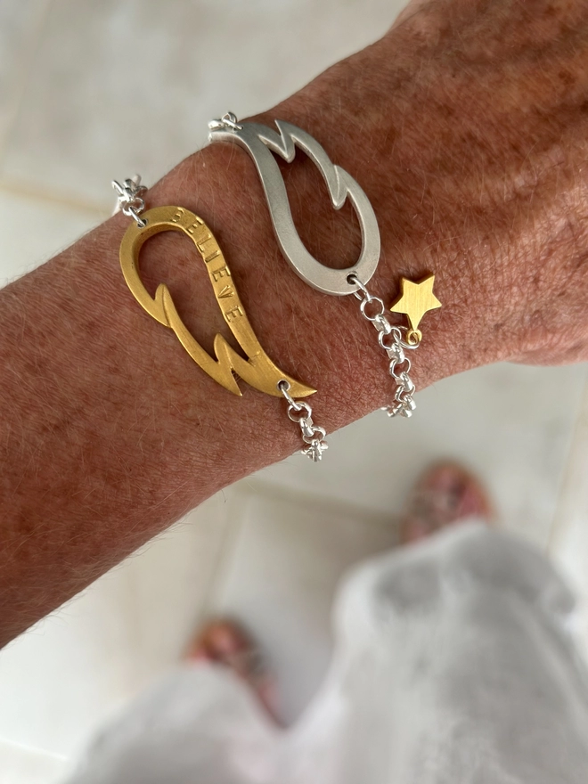 model wears a personalised gold wing charm on a silver belcher chain bracelet with a silver mini star