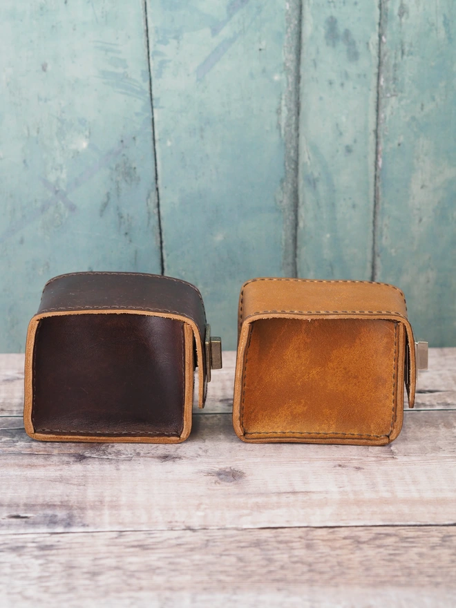 Handmade leather watch cases in side profile, showing the box corner stitching.