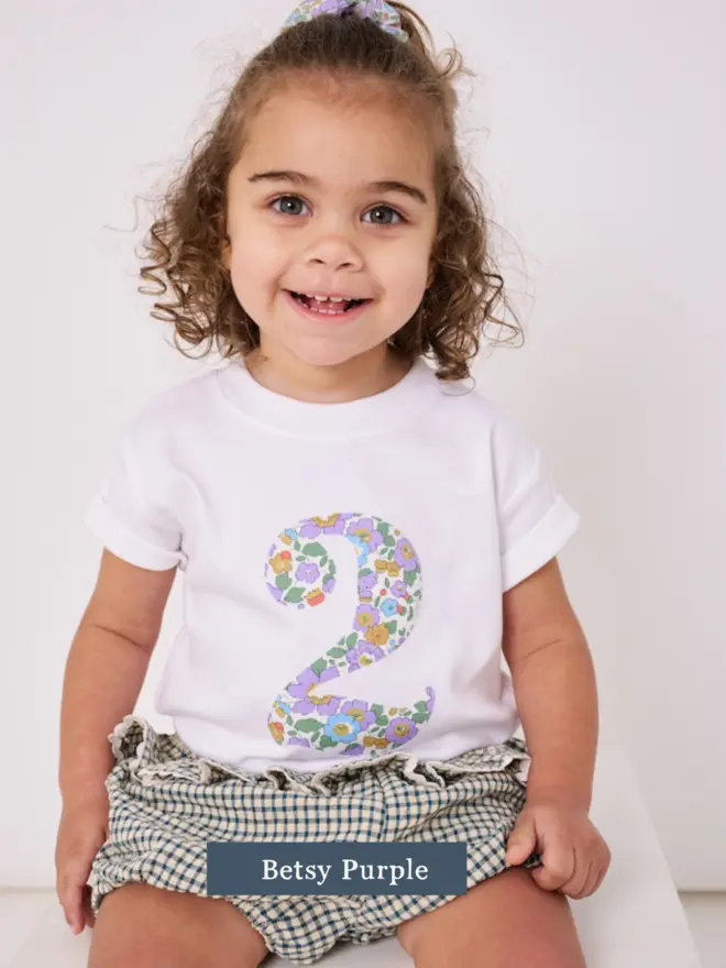 a 2 year old girl wearing a white birthday t-shirt with a number 2 cut from liberty floral print on the front