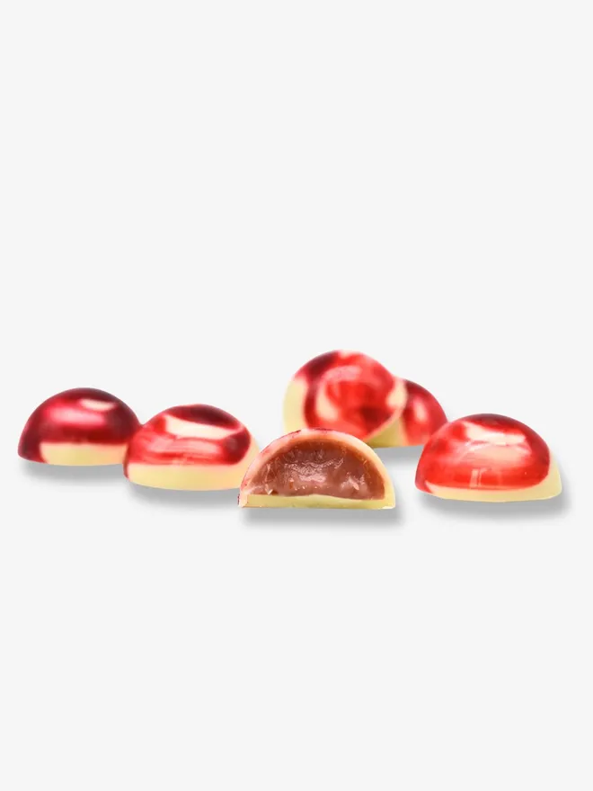 6 luxury white chocolates with one cut in half revealing a strawberry cream filling