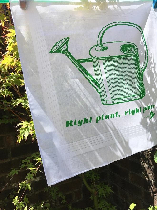 A Mr.PS Right Plant Right Place handkerchief printed in green on a washing line in a sunny garden