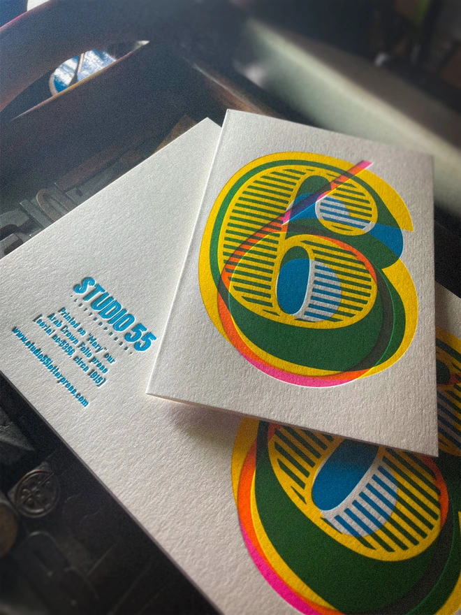 Handmade letterpress 6th birthday card featuring bold overlapping numerals printed in vibrant fluorescent cyan, magenta and yellow inks. Each card is individually hand printed using traditional letterpress techniques on luxury paper stock, creating a beautifully tactile finish with a deep impression and rich layered colours inspired by the CMYK printing process. Printed on a traditional letterpress from 1915.