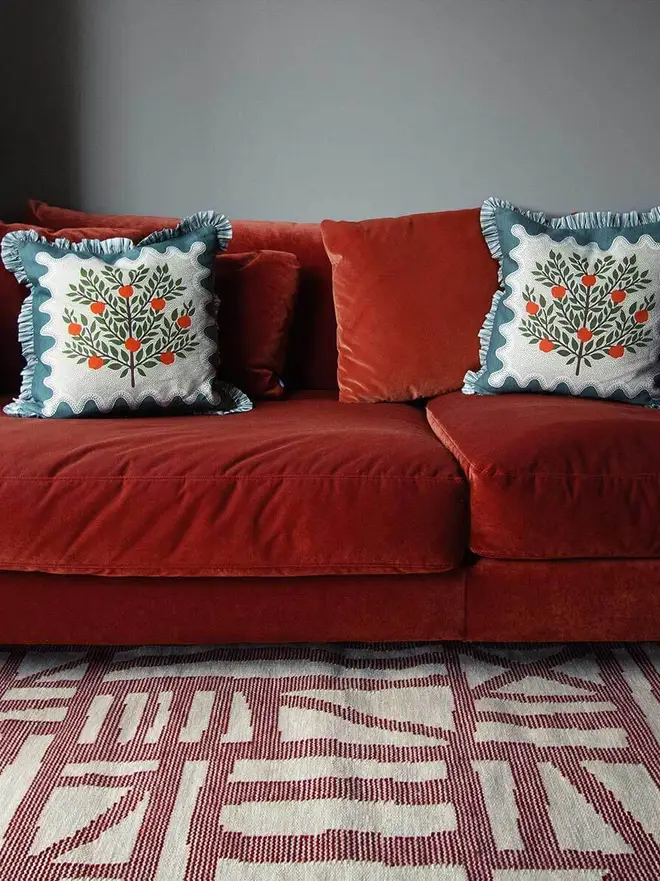 Tudor Flatweave Rug, a colourful rug in a living room. It is surrounded by other household items. 