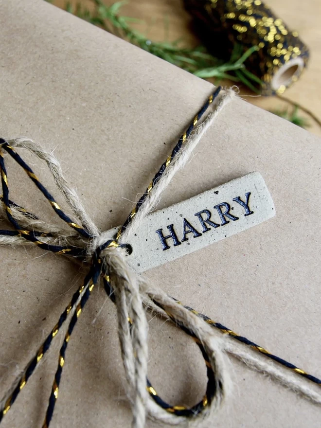 brown gift ribboned with metallic twine and a personalised ceramic tag