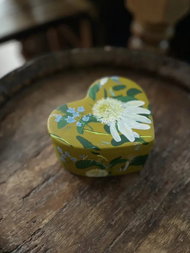 hand painted floral heart shaped keepsake box background in a olive green with white echinaceas and  blue forget me not flowers