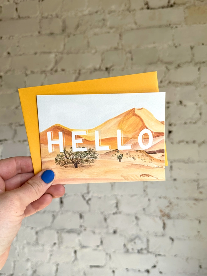  a greetings card featuring an illustration of some of the Everglades landscape with the text “hello” with a deep yellow envelope