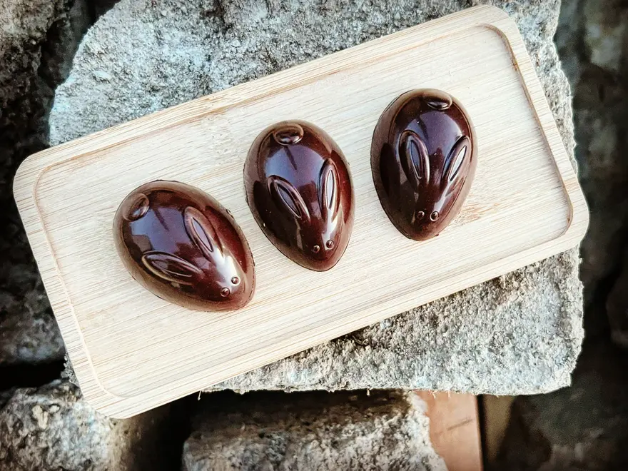 Chocolate Caramel Filled Bunnies 60% (Box Of 3), some chocolate rabbits sitting on a wooden tray. 