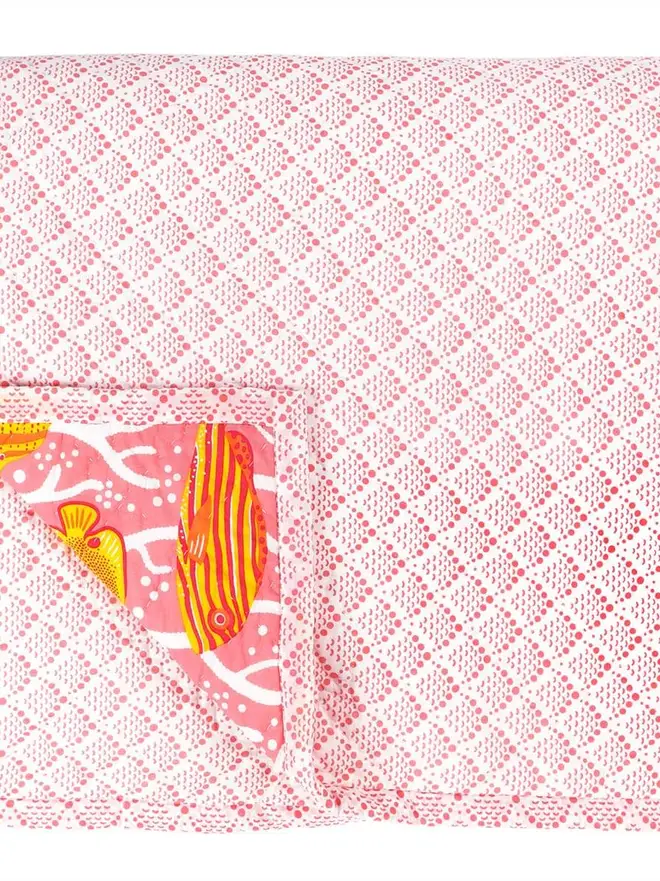 Pink Coral Reef Quilt, a pink quilt sitting on a white surface. 