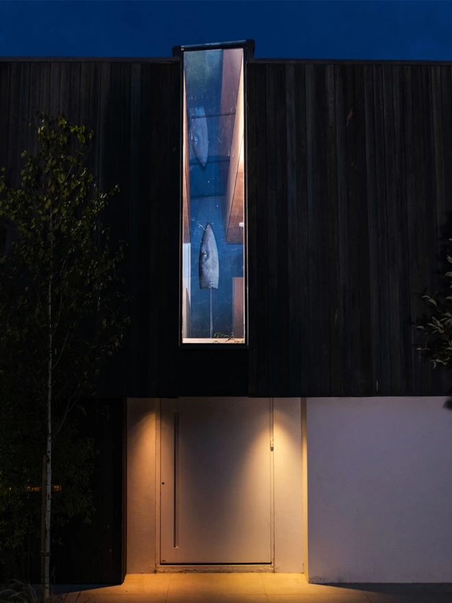 Contemporary house showcasing the dogfish surfboard through a n outside window