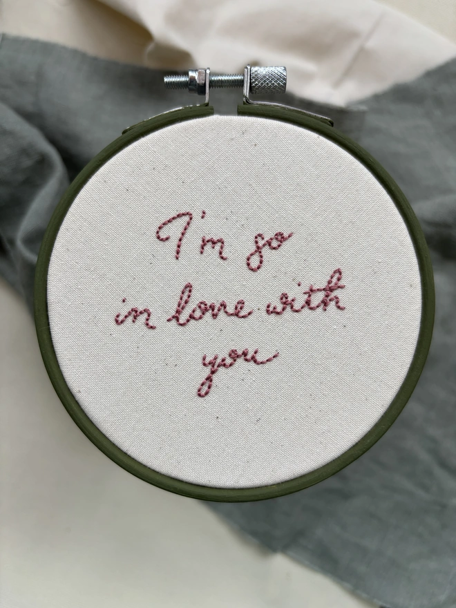 I’m so in love with you hand embroidered dusky pink lettering on natural calico in olive green hoop